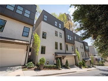 Contemporary townhome showcasing a white painted brick facade, symmetrical window placement, and individual garage entries at 1821 Huntington Hills Nw Ln, Atlanta, GA 30309