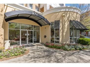 Building entrance featuring glass doors under an awning and surrounded by colorful flowerbeds at 870 Inman Village Pkwy # 203, Atlanta, GA 30307