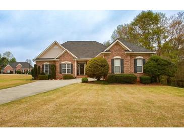 Charming brick home featuring manicured front lawn and complemented by mature trees at 118 Jasmine Way, Carrollton, GA 30180