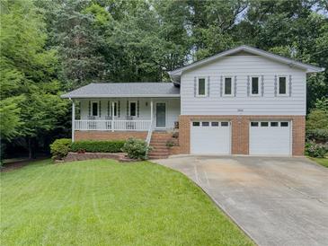 Charming home featuring a brick facade two-car garage, covered porch, and landscaped front yard at 5841 Covered Wagon Trl, Lilburn, GA 30047