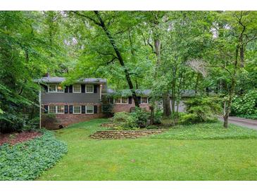 Charming home featuring a lush green lawn and mature trees for a private setting at 220 N Springs Ct, Sandy Springs, GA 30328