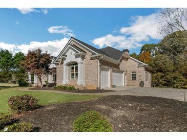 Charming brick home with a two-car garage, landscaped yard, and a well-maintained lawn on a sunny day at 6740 Mountain Lake Ln, Cumming, GA 30028