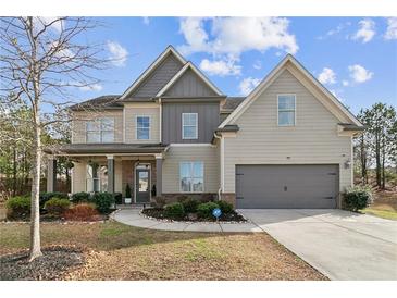 Two-story home featuring a well-manicured front yard, attached garage, and charming covered porch at 2496 Osceola Rd, Lithonia, GA 30058