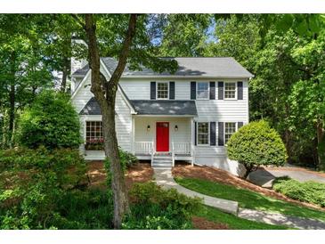 Charming two-story home with a red front door, black shutters, and a well-manicured lawn, nestled in a lush, green landscape at 3214 Woodleaf Ct, Marietta, GA 30062