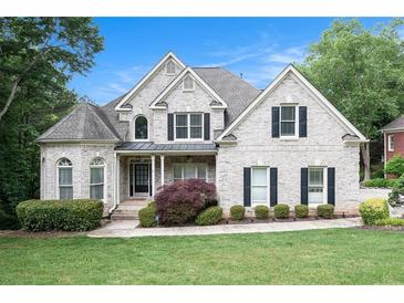Charming two-story home with a manicured lawn, lush landscaping, and a classic white brick facade at 1640 Settindown Dr, Roswell, GA 30075