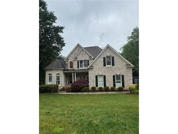 Charming two-story home with brick and stone exterior and well-manicured front lawn at 1640 Settindown Dr, Roswell, GA 30075