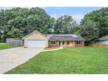 Charming single-story home with an attached garage, solar panels, and a well-maintained front lawn at 35 Riverbend Dr, Covington, GA 30014