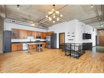 Open kitchen with stainless steel appliances, wood cabinets, a dining table, and a modern chandelier at 660 Glen Iris Dr # 206 & 109, Atlanta, GA 30308