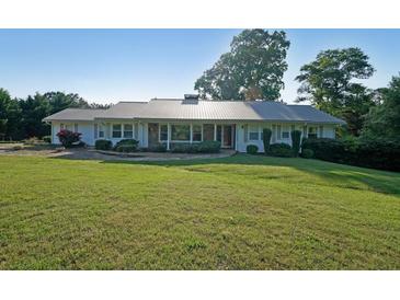 Beautiful ranch-style home featuring a metal roof, stone accents, and a spacious front yard at 1001 Wiley Bridge Rd, Woodstock, GA 30188