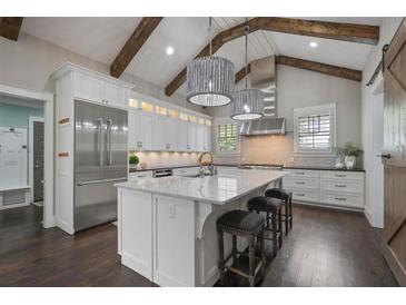 Modern kitchen featuring stainless steel appliances, a large island, and elegant lighting fixtures and wooden beams at 2908 Mabry Ne Ln, Brookhaven, GA 30319