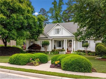 Charming traditional home featuring a manicured lawn, lush landscaping, and a welcoming front porch at 450 Bay Grove Se Rd, Loganville, GA 30052