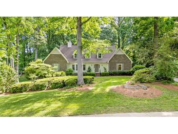 Charming two-story brick home with manicured landscaping and mature trees provides shade on a sunny day at 50 Stonington Pl, Marietta, GA 30068