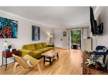 Bright living room with hardwood floors, a comfortable couch, and sliding glass doors to the balcony at 1177 Church St # A, Decatur, GA 30030