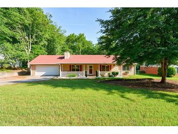 Charming home featuring a well-manicured lawn, inviting front porch, and attached garage at 1420 Hillside Se Pl, Conyers, GA 30094