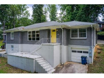 Charming home featuring a gray brick facade, a bright yellow front door and a well-maintained front yard at 2564 Riggs Dr, East Point, GA 30344