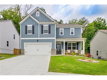 Charming two-story home featuring a well-manicured lawn, attached garage, and inviting front porch at 7730 Demeter Dr, Fairburn, GA 30213