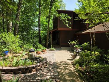 Landscaped pathway leading to a brown two-story home surrounded by lush trees at 406 Vivian Way, Woodstock, GA 30188