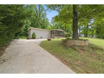 Charming single-story home with a long driveway and a screened in front porch surrounded by lush greenery at 1447 High Sierra Dr, Lawrenceville, GA 30043