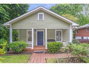 Charming bungalow with a covered front porch, blue door, and lush landscaping at 1265 Woodland Se Ave, Atlanta, GA 30316