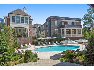 Upscale community pool with lounge chairs and umbrellas situated near brick and white trim buildings at 100 Sheridan Dr, Atlanta, GA 30305