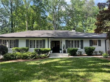 Charming single-story home with classic white brick, black trim and shutters, complemented by a lush green lawn and mature trees at 1343 Peachtree Battle Nw Ave, Atlanta, GA 30327