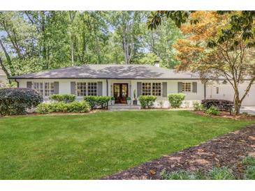 Charming traditional home with a manicured lawn, symmetrical landscaping, and a welcoming facade with many windows at 1343 Peachtree Battle Nw Ave, Atlanta, GA 30327