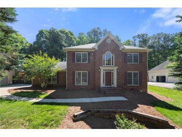 Charming two-story brick home with a well-manicured lawn and mature trees on a sunny day at 227 Eton Ct, Mableton, GA 30126