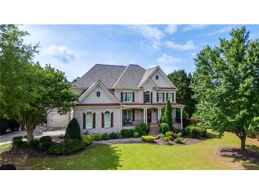 Stunning two-story home with lush landscaping, brick facade, covered porch and attached two-car garage at 100 Braxton Way, Roswell, GA 30075