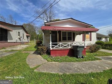 Exterior shot of home featuring a red and white color scheme, concrete driveway, and small front yard at 1243 Hill Nw St, Conyers, GA 30012