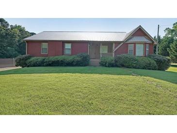 Charming home featuring a metal roof, well-maintained lawn, and mature landscaping at 999 Wiley Bridge Rd, Woodstock, GA 30188
