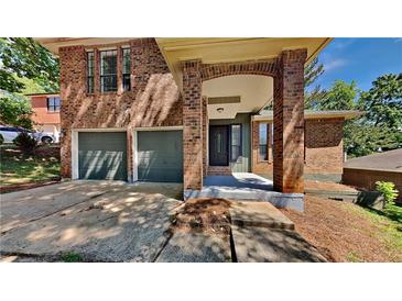 Charming two-story brick home featuring an attached two-car garage and a welcoming front entrance at 516 N Shore Rd, Lithonia, GA 30058