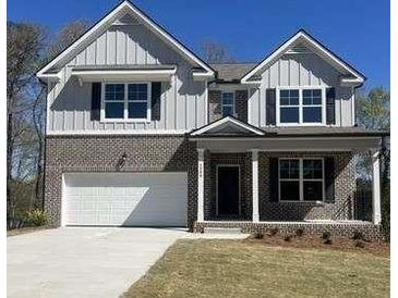 Charming two-story home features a brick facade, gray siding, an attached two-car garage, and manicured lawn at 3064 Steinbeck Way, Atlanta, GA 30344