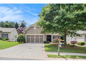 Charming home featuring a two-car garage, lush lawn, and mature landscaping at 4445 Vanadium Bend, Cumming, GA 30040