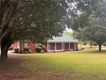 Charming brick home featuring a metal roof, manicured landscaping, and a welcoming front porch at 2620 Dr Bramblett Rd, Cumming, GA 30028