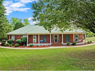 Charming brick home with a metal roof, welcoming front porch, and lush landscaping at 2620 Dr Bramblett Rd, Cumming, GA 30028