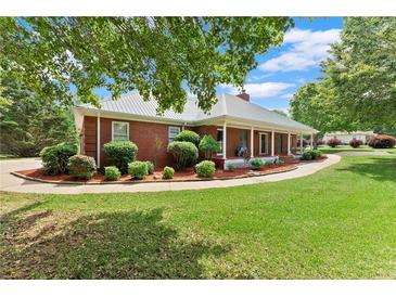 Charming single-story brick home with a metal roof, manicured lawn, and inviting front porch at 2620 Dr Bramblett Rd, Cumming, GA 30028