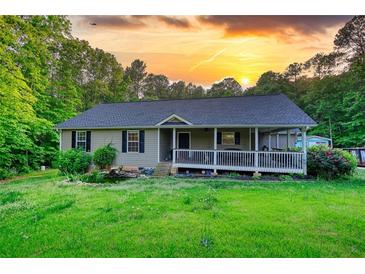 Charming single-story home with a covered porch and lush landscaping at sunset at 160 Riverbrooke Trl, Covington, GA 30016