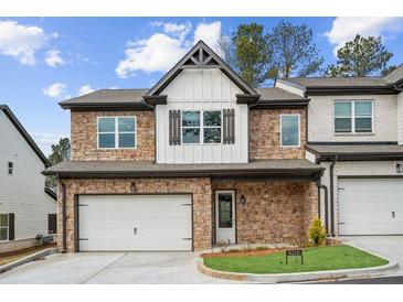 Beautiful two-story townhome featuring stone accents, white siding, and a two-car garage at 8210 Sonata Ln, Cumming, GA 30041