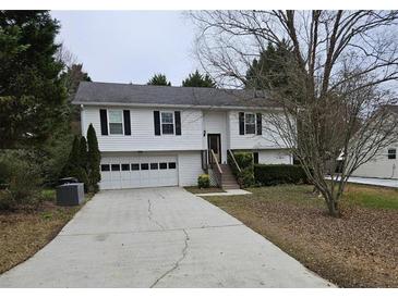 Charming home featuring a two-car garage, landscaped front yard, and welcoming entrance stairs at 2811 Country Farms Ct, Snellville, GA 30039