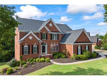 Charming two-story brick home with a manicured lawn and classic architectural details at 5260 Harbury Ln, Suwanee, GA 30024