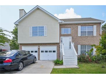 Charming two-story home with brick and vinyl siding, attached garage, and well-maintained front yard at 7169 Sweet Gum Ct, Lithonia, GA 30058