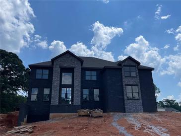 Striking two-story home with large windows and stone accents, set against a bright blue sky at 3066 Reserve Sw Ct, Conyers, GA 30094