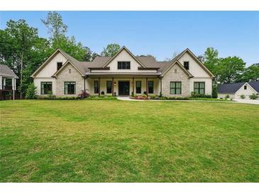 Beautiful home featuring a well-manicured lawn, stone accents, and a covered porch perfect for relaxing at 131 Forsyth Park Ln, Woodstock, GA 30188