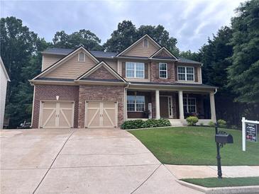 Charming two-story home with a manicured lawn, attached two-car garage, and a welcoming front porch at 6725 Grove Meadows Ln, Cumming, GA 30028