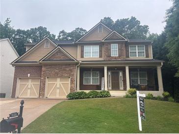 Charming two-story home with stone accents, covered front porch, and a manicured lawn at 6725 Grove Meadows Ln, Cumming, GA 30028