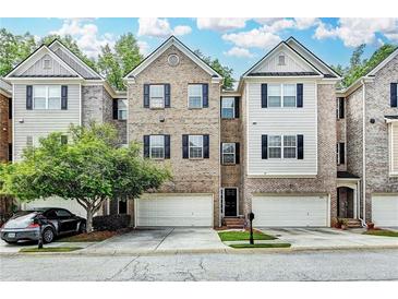 Charming townhome featuring a brick facade, attached garage, and neatly landscaped front yard at 2173 Pebble Beach Dr, Lawrenceville, GA 30043