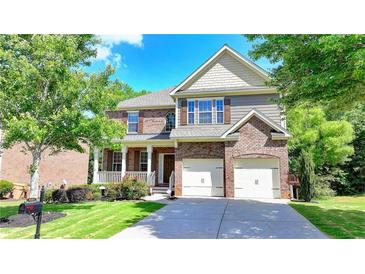 Two-story brick home featuring a manicured lawn, an attached garage, and a covered porch at 4885 Maristone Landing Way, Cumming, GA 30040