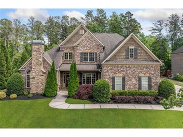 Stately brick home featuring manicured landscaping, a stone chimney, and classic architectural details at 390 Scott Farm Dr, Powder Springs, GA 30127