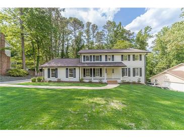 Inviting two-story white brick home featuring black shutters and a meticulously maintained front lawn at 4367 Cedar Wood Sw Dr, Lilburn, GA 30047
