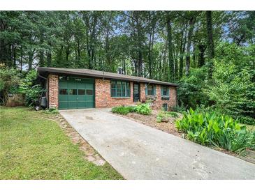 Charming brick home features a well-manicured lawn, landscaping, and an attached garage at 1094 Seville Dr, Clarkston, GA 30021